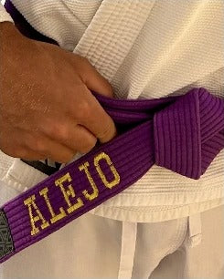 ALEJO embroidered in gold thread along a purple belt