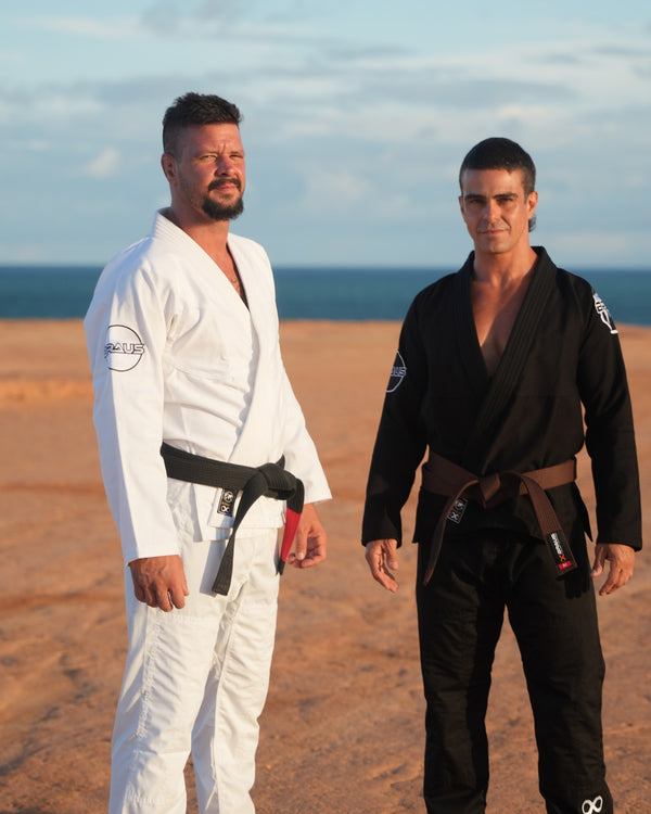 Two training partners in white and black gis on the coast at sunset